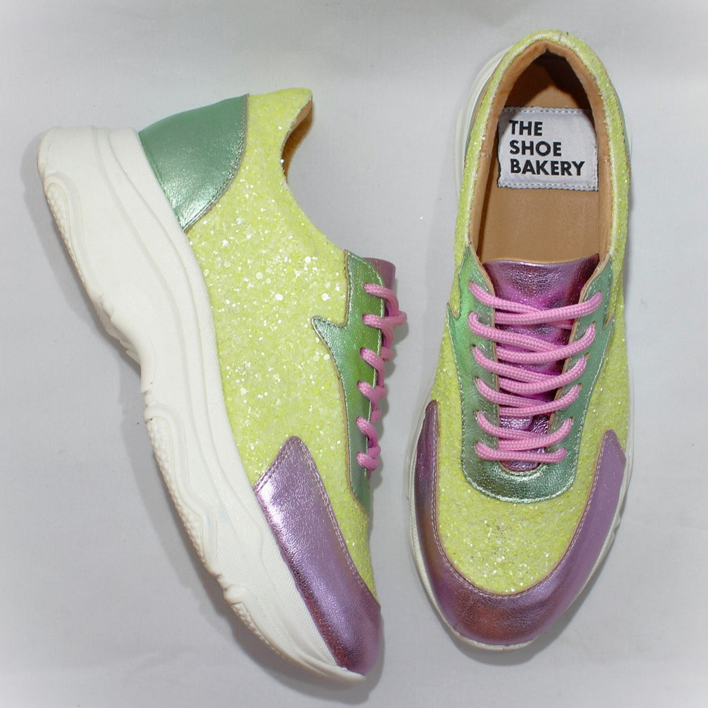 Ett par glittriga skor i rosa grönt och gult. The Shoe Bakery