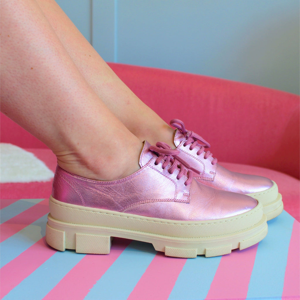 Ett par fötter med rosa skor, rosa snörskor, beige sula, The Shoe Bakery
