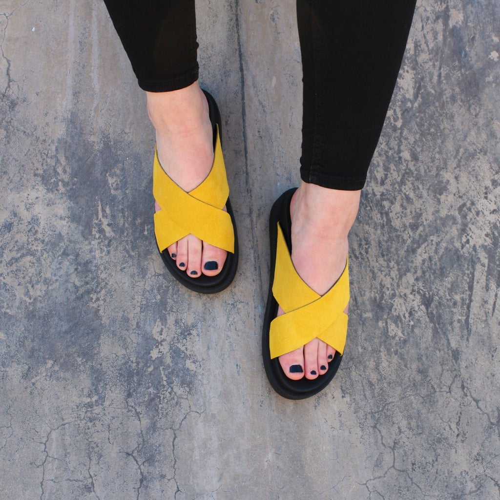 ett par fötter som bär gula sandaler i mocka The Shoe Bakery