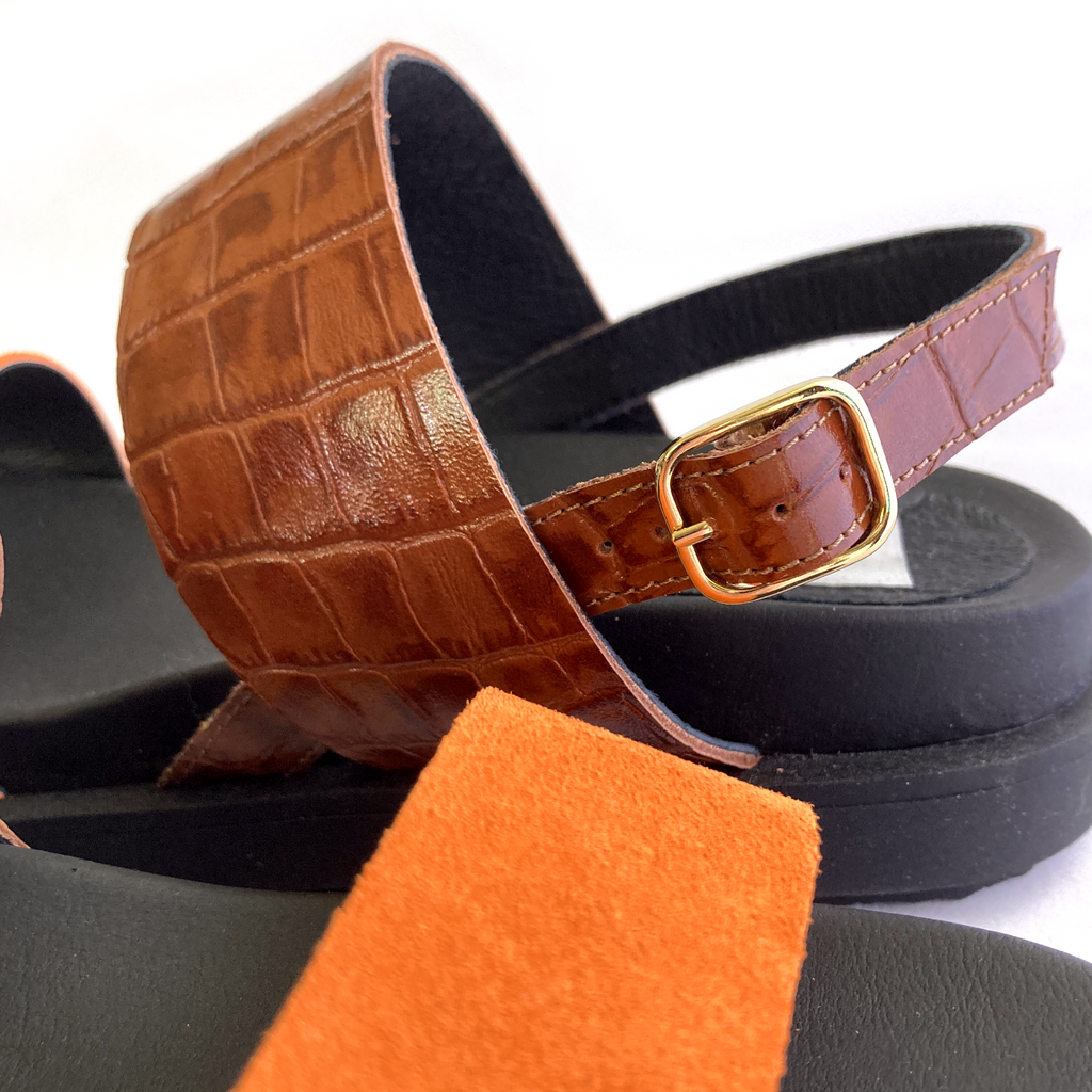 en detaljbild på ett par sandaler. Orange mocka och brunt croco präglat läder. litet guldspänne. The Shoe Bakery